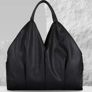 Black leather handbag on a textured white surface with a light gray background